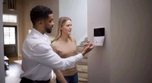 man and woman looking at digital thermostat on the wall and talking