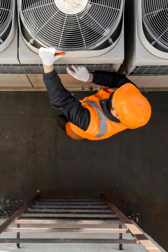 man in hard hat working on the hvac unit on the roof of a commercial building