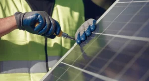 technician with helmet installing a solar panel using a screwdriver