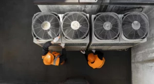 two men in hard hats working on the hvac unit on the roof of a commercial building